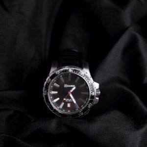 Close-up of a stylish wristwatch displayed on dark fabric with a detailed face.