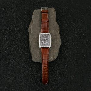 A luxurious wristwatch with a brown leather strap elegantly placed on a stone backdrop.