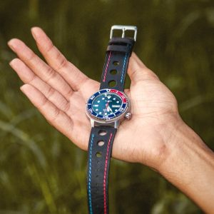 Close-up of a classic analog watch with leather strap held in a hand outdoors, showcasing elegant design.