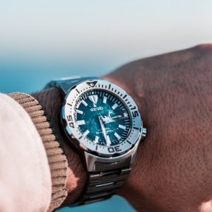 Stylish silver wristwatch with a detailed face and bracelet on a wrist in outdoor setting.